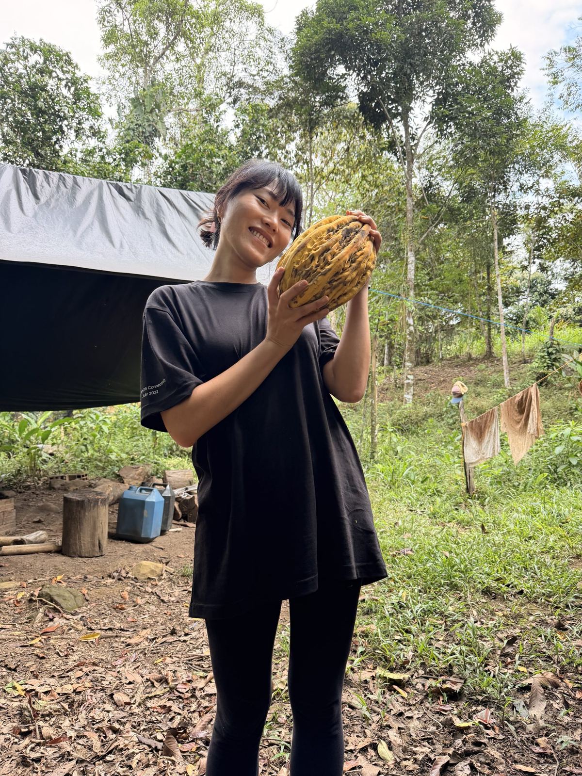 Min holding a cacao pod on the land