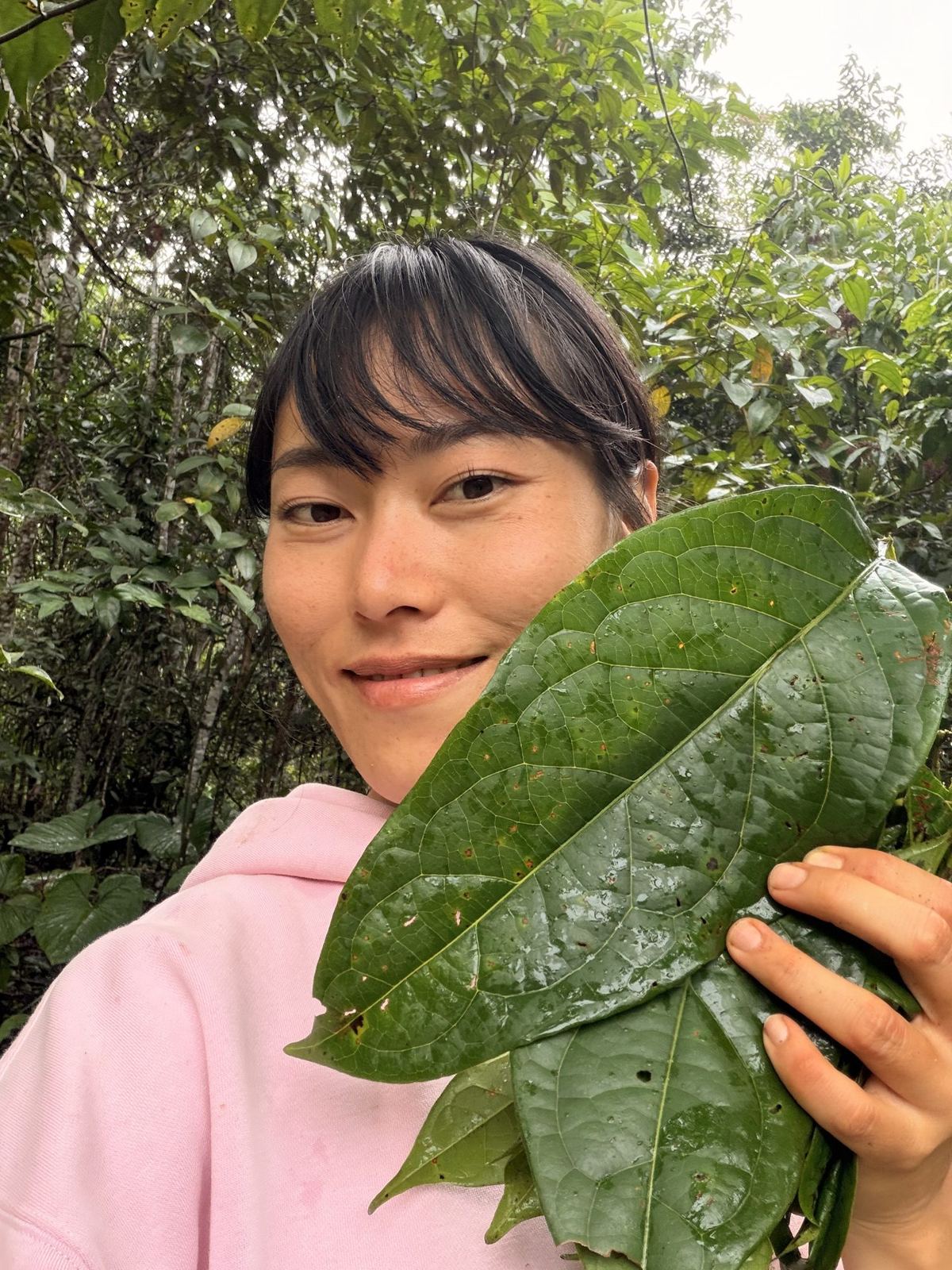 Min holding a large leaf in the forest near Mocoa